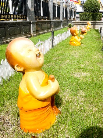 kid monk mini figure acting on grass unusualの写真素材