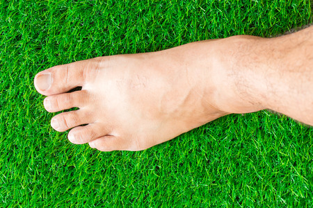 nude foot touch on green grass texture background eco conceptの写真素材