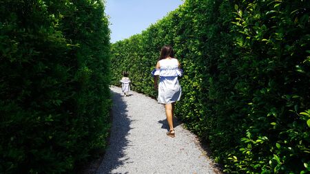 child and mom escape maze green plant wall