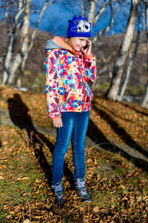 Little girl speaking by phone in forestの写真素材