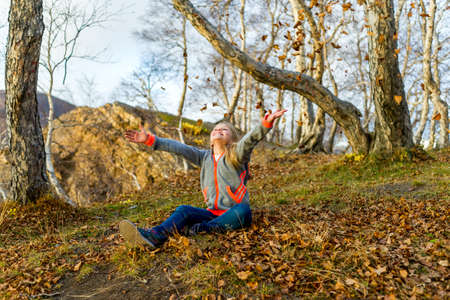 Happy little girl throwing autumn leavesの写真素材