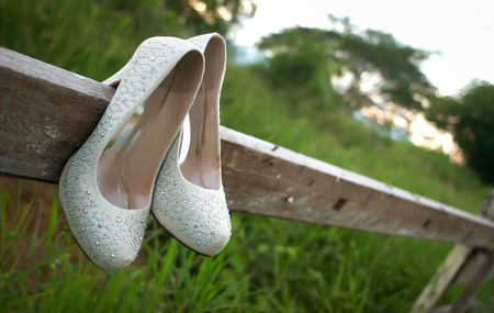 bride wedding shoes hooked at the wooden fence at the grass fieldの写真素材