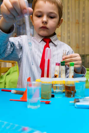 The boy enthusiastically studying chemistry and makes his first experience in chemicalの写真素材