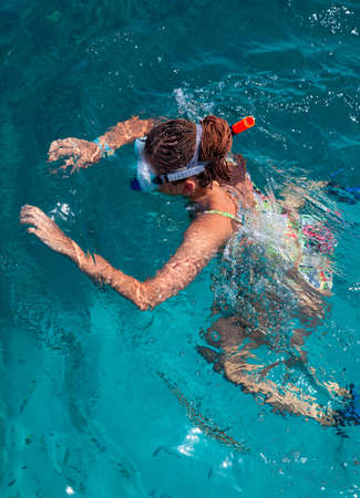 A woman wearing a mask and flippers diving in the shallows in a turquoise seaのeditorial素材