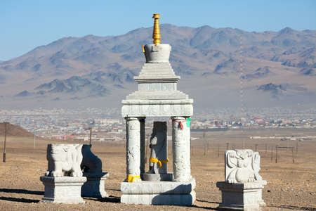Buddhist stupa in the mountains of Mongolia on the background of the settlementの写真素材