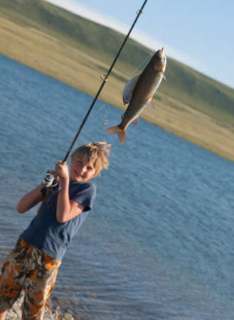 The boy with a spinning catch grayling  Beautiful fish in mountain lakes and riversの写真素材