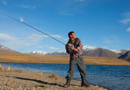 Asian fisherman throws spinning in a mountain lake