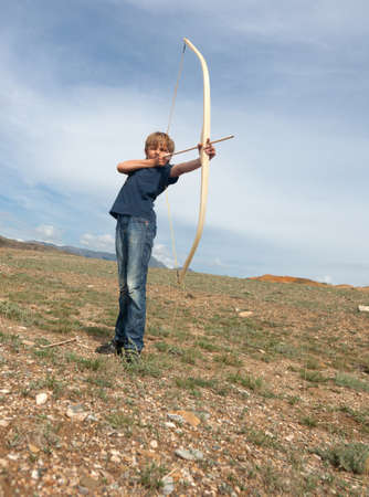 Boy shoots a bow at a target, in the open airの写真素材