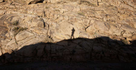 Shadow of a man on a rock in the mountainsの写真素材