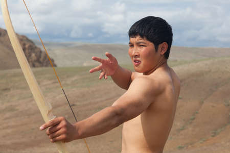 A young man shoots a bow. A man of Asian appearanceの写真素材