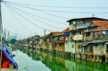 Poor area with Slum house on the edge of a canal in Jakarta, Indonesiaの写真素材