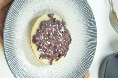 Serabi the indonesian traditional Pancakes made from coconut milk, with chocolate topping on white plate on wooden tray.の写真素材