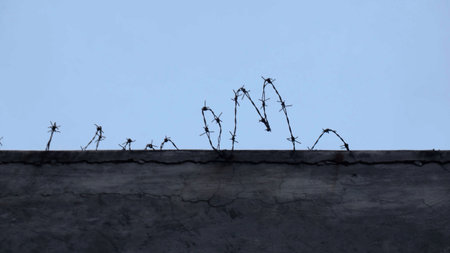 Coiled Barbed Wire Installed on Top of a High Concrete Wall for Enhanced Security and Property Boundary Protectionの写真素材