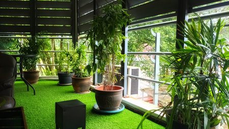 Peaceful Relaxing Area on an Upstairs Terrace Featuring Green Synthetic Grass and Various Potted Tropical Plantsの写真素材