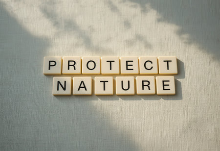 Letter tiles spelling "Protect Nature" arranged on a soft fabric background. This image promotes environmental awareness and the importance of preserving our planet for future generations.の素材