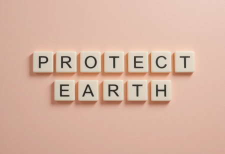 Creative wooden letter tiles spell out the message "Protect Earth" on a soft pink background, promoting environmental awareness and sustainability in a minimalist style.の素材