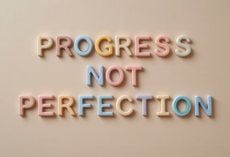 A vibrant and playful display of the quote "Progress Not Perfection" presented in colorful letters on a soft wall background, emphasizing positivity and motivation.の素材