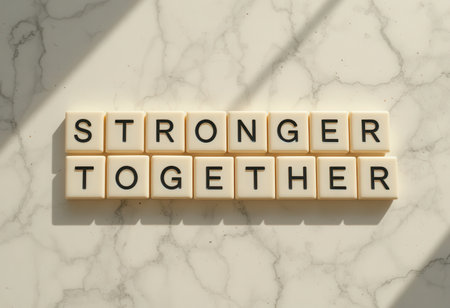 A close-up view of letter tiles arranged to spell "Stronger Together" on a marble background. This image conveys a powerful message of unity and support.の素材