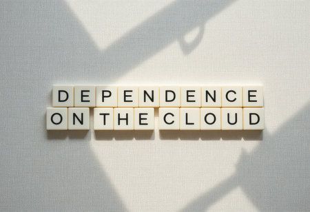 Conceptual image featuring letter tiles spelling "Dependence on the Cloud" with shadows on a textured background. Ideal for illustrating digital reliance.の素材