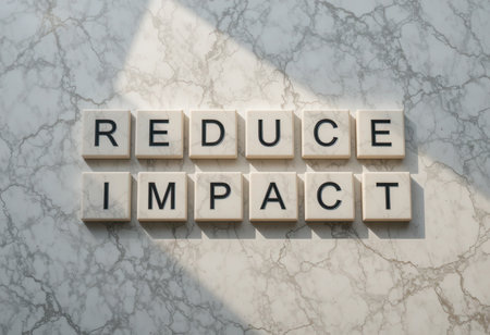 A powerful message reading "Reduce Impact" displayed on a white marble surface, illuminated by natural light, promoting awareness for environmental responsibility and sustainability.の素材