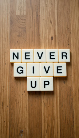 A visually engaging composition featuring letter tiles arranged to spell "Never Give Up," highlighting themes of motivation and encouragement on a wooden surface.の素材