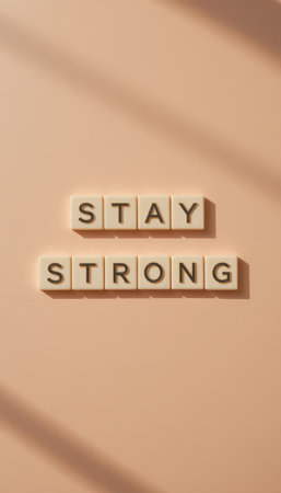 A minimalist composition featuring the words "Stay Strong" in soft beige letters on a light pink background. This image promotes positivity and resilience.の素材