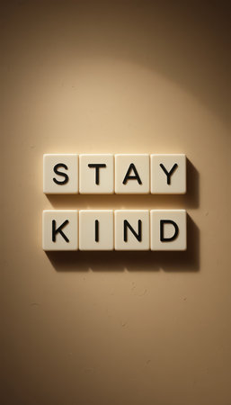 A visually striking image featuring the words "Stay Kind" arranged neatly on a smooth wall, casting gentle shadows, serving as a reminder to embrace kindness daily.の素材