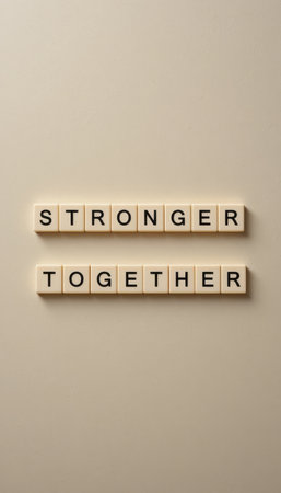 This image features the phrase "Stronger Together" displayed artistically using letter tiles against a neutral background, symbolizing unity and empowerment.の素材