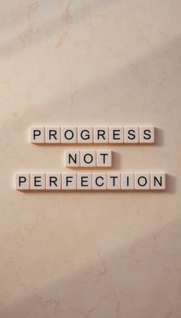 Inspirational message "Progress Not Perfection" displayed in tiles on a marble background. A visual reminder for self-improvement and motivation. Perfect for personal growth themes.の素材