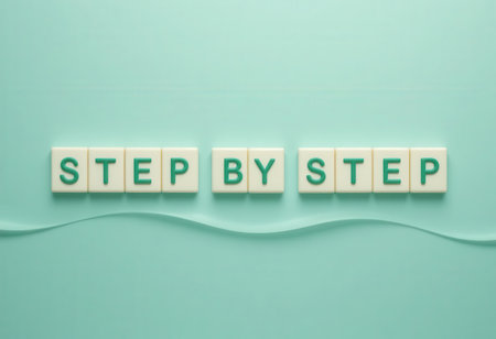 This image features letter tiles arranged in the phrase "STEP BY STEP" against a soft pastel background. Ideal for conveying motivation and guidance in learning.の素材