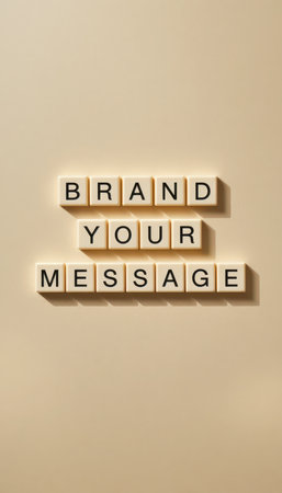 A minimalist arrangement of letter tiles spells out "BRAND YOUR MESSAGE" on a smooth, neutral background, ideal for creative branding visuals.の素材