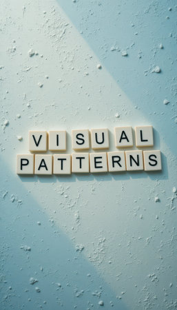 This stock photo showcases an artistic arrangement of letter tiles spelling "VISUAL PATTERNS" on a textured blue background, embodying creativity and design inspiration.の素材
