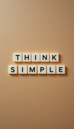 Beautifully arranged letter tiles spell out 'Think Simple' on a warm background, conveying a powerful message of clarity and focus for personal and professional growth.の素材