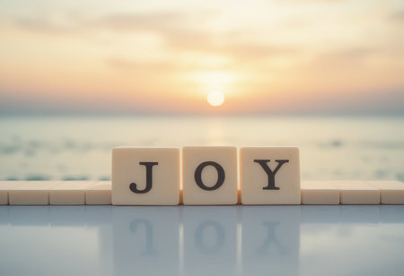 The image showcases the word "joy" crafted from letter blocks, set against a serene beach sunset. Soft pastel hues create a calming atmosphere, symbolizing happiness and tranquility.の素材