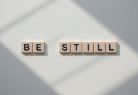 The image features the motivational phrase "Be Still" created with tiles in a serene indoor environment. Soft lighting and shadows enhance its calming effect.の素材
