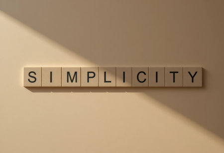 A minimalistic arrangement of tiles forming the word "Simplicity" casts soft shadows against a neutral background, evoking calmness and clarity in design.の素材