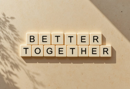 The image showcases the phrase "Better Together" formed with letter tiles on a beige surface, casting soft shadows that evoke a serene atmosphere.の素材
