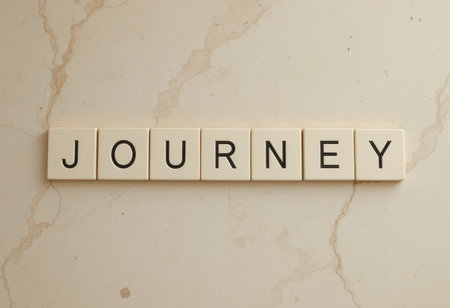 A close-up of the word "Journey" displayed with letter tiles on a light marble surface. This image represents exploration, creativity, and the adventure of life.の素材