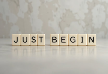 A motivational image featuring block letters spelling "JUST BEGIN" against a neutral background, symbolizing the start of a new journey or project. Perfect for uplifting content.の素材