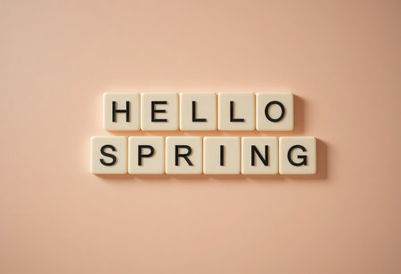 A cheerful display of letter tiles spelling "Hello Spring" on a soft pink background, symbolizing renewal and the arrival of the spring season perfect for various projects.の素材
