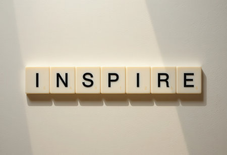 The image showcases the word "Inspire" formed with letter tiles against a light background. Shadows subtly enhance the composition, embodying creativity and motivation.の素材