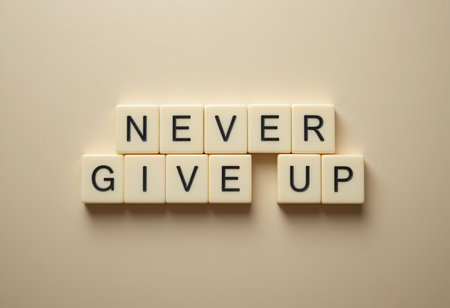 This image features the motivational phrase "Never Give Up" created with letter tiles on a soft cream background. Ideal for inspiration and positivity themes.の素材