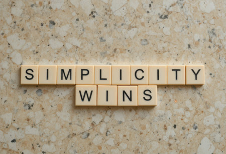 A stylish arrangement of letter blocks spelling "Simplicity Wins" against a textured surface. This design emphasizes the beauty of simplicity and clarity in communication.の素材