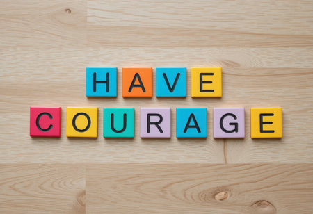 Colorful letter tiles on a wooden surface spell out "Have Courage," promoting positivity and motivation. Perfect for inspirational content.の素材