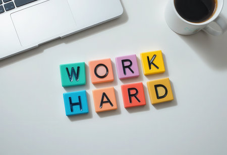 A vibrant flat lay of colorful letter tiles spelling "WORK HARD" beside a coffee mug and a laptop. This image promotes motivation and productivity in a modern workspace.の素材