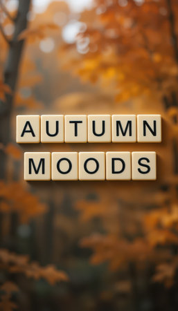A captivating autumn scene featuring letter tiles spelling "Autumn Moods" set against a softly blurred forest of orange leaves, evoking tranquility and warmth.の素材
