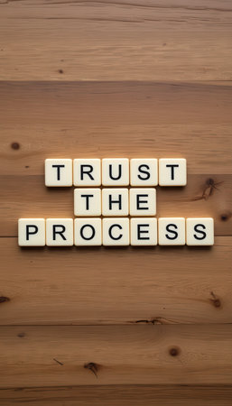 A motivational arrangement of letter tiles spelling "Trust the Process" on a warm wooden background, symbolizing belief in growth and perseverance.の素材