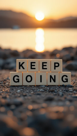 A beautifully captured moment featuring the words "Keep Going" on stones by a serene water body during sunset, symbolizing hope and perseverance in nature.の素材