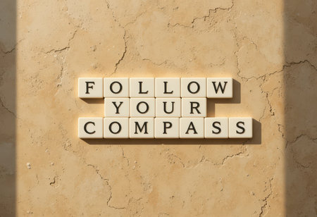 A motivational arrangement of letter tiles spelling "FOLLOW YOUR COMPASS" set against a textured background, evoking guidance and inspiration on one's journey.の素材