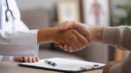 A close-up of a doctor and patient engaging in a handshake, symbolizing trust and cooperation in healthcare settings during consultations.の素材